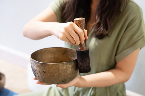 Playing the singing bowl instrument with finesse, a young Asian woman showcases her skills