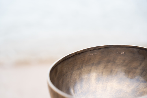 With a narrow focus, the lens reveals the intricate patterns and textures adorning a singing bowl, highlighting its cultural richness and timeless allure