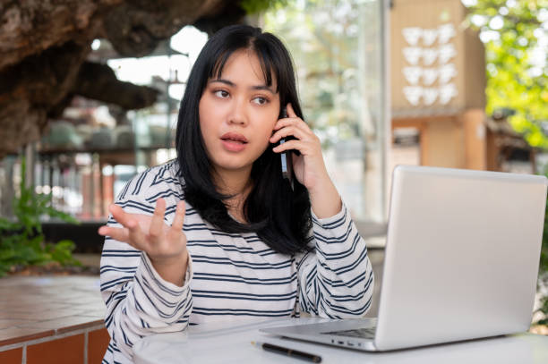 istock A serious Asian woman is talking on the phone with someone while working remotely at a cafe. 2007014633