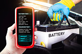 Battery tester in a car mechanic hand for testing battery voltage and battery health