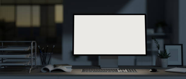 A modern, dark office at night with a white-screen computer mockup and office supplies on the desk. A modern, dark office at night with a white-screen computer mockup and office supplies on the desk. 3d render, 3d illustration office window night stock pictures, royalty-free photos & images