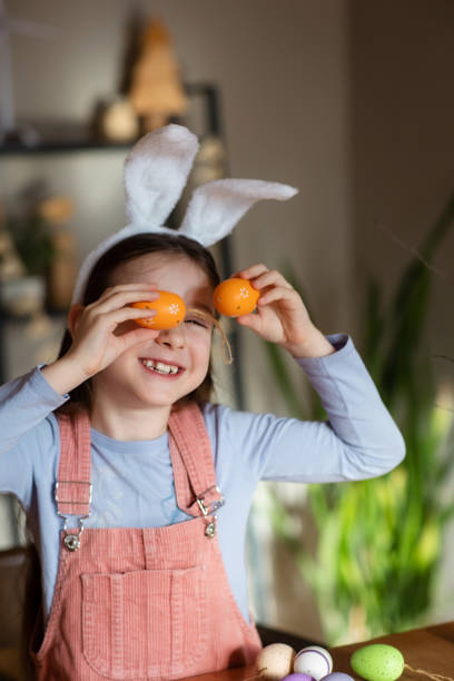 istock funny child girl playing with Easter eggs at table at home 2007027958