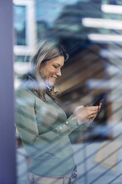 istock Happy woman using mobile phone by the window. 2007046647