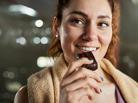 Happy woman eating protein bar on a break from sports training.
