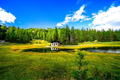 Krallersee on the high plateau of the Tauplitzalm with a small hut. View of the lake at the Totes Gebirge in Styria. Idyllic landscape with green nature and a lake on the Tauplitz.