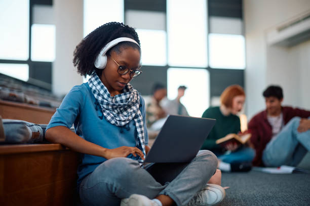 istock Black female student with headphones e-learning on laptop at campus. 2007102013