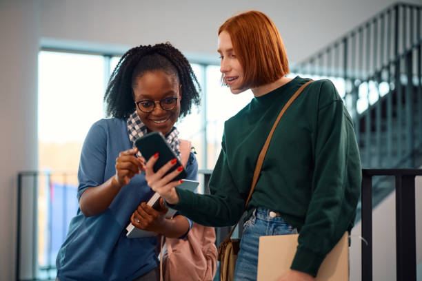 istock Happy female students using mobile phone in a hallway at the university. 2007104678