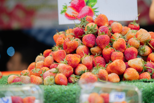 Organic and fresh strawberries on green grass table prepare and ready for sale in farmer market. Selective focus.