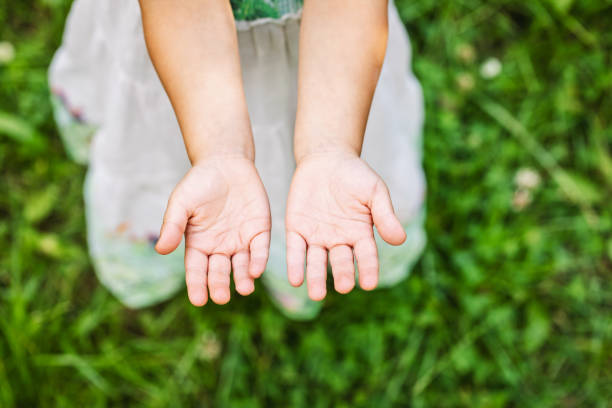 A child displays their fists in a playful and confident manner, symbolizing strength and innocence, with a blurred background of a cozy home environment.