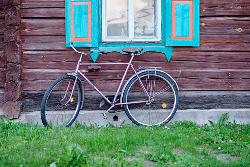 An old bicycle on the background of an old house. The concept of developing and replacing everything old with new