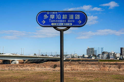 On a sunny day in February 2024, along the Tama River in Kawasaki City, Kanagawa Prefecture, a road sign for the road along the Tama River stands on the Tama River bank.
