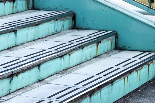 Stock photo showing close-up view looking up a modern, bright, multicoloured staircase. Rainbow effect achieved from painting steps red, blue, green, yellow and orange.