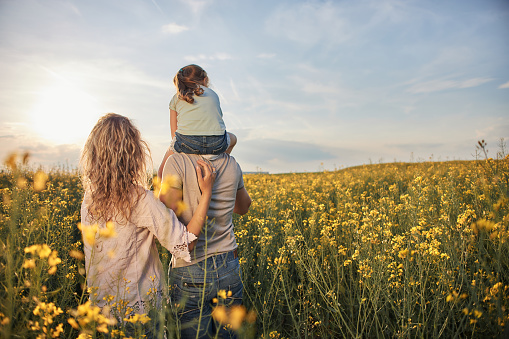 Young mother, father and daughter in field on a sunset.