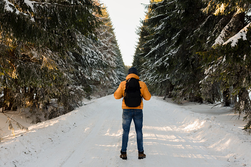 Man with yellow jacket and backpack is hiking in the winter