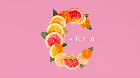 Vitamin C on pink background, slice of citrus orange, lemon flat lay creative composition