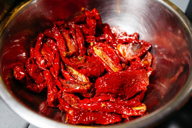 Close-up of glistening sun-dried tomatoes in a reflective metal bowl, rich in color and texture, ready for culinary use.