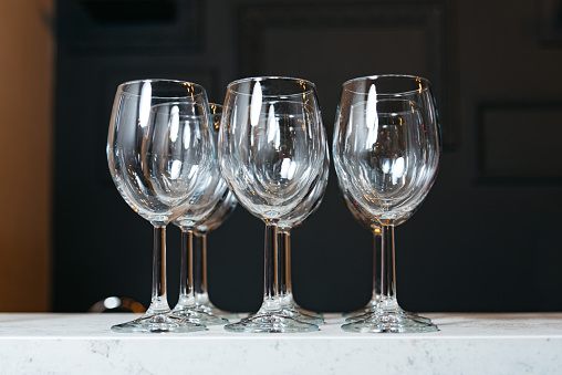 A set of four empty crystal wine glasses displayed on a white marble countertop, reflecting light beautifully.