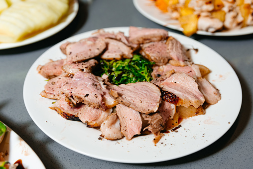 Herb-crusted roast pork sliced and plated with garnish, showcasing the juicy tenderness and savory flavors of the meat.