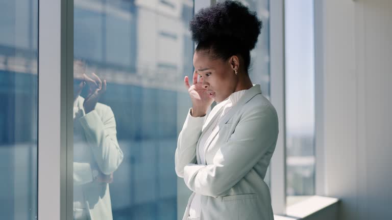 Anxiety, headache or stress and business black woman at window of office with worry for mistake or fail. Burnout, pain or fatigue and unhappy young employee in corporate workplace with debt or loss