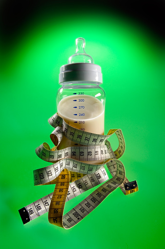 Baby bottle and measure tape.isolated on a green background.
High angle view, Studio shot: