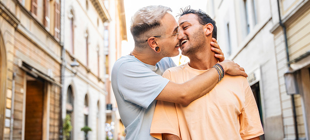 Young gay couple hugging and kissing in city street - Happy homosexual guys celebrating pride day together - Lgbt concept