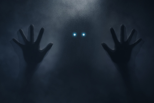 Silhouetted hands reaching towards glowing eyes in the darkness, creating a suspenseful atmosphere of an otherworldly encounter.