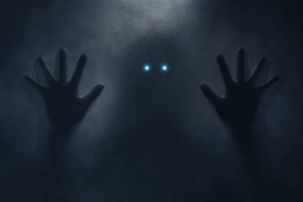 Mysterious Entity Encounter Silhouetted hands reaching towards glowing eyes in the darkness, creating a suspenseful atmosphere of an otherworldly encounter. creepy glowing eyes stock pictures, royalty-free photos & images
