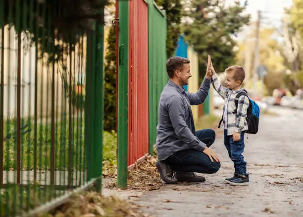 navigating the intersection of, a father and song giving high five on the entrance of kindergarten