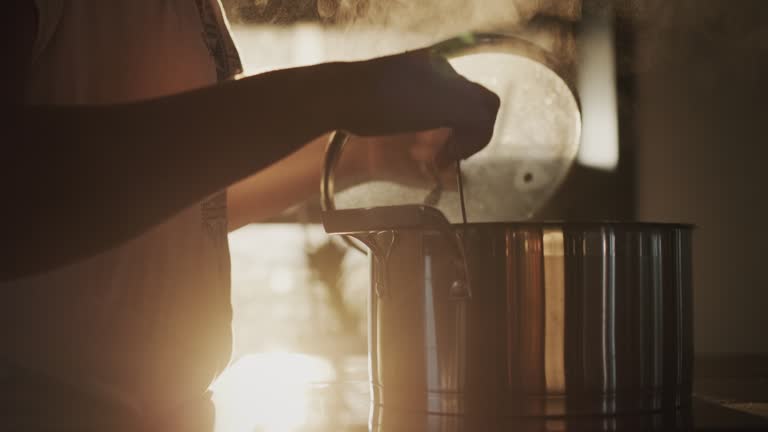 A housewife is cooking soup in a pot in her kitchen, the setting sun is shining from the window