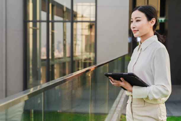 istock Young Asian woman on a balcony with a tablet, AI-generated. 2007373214