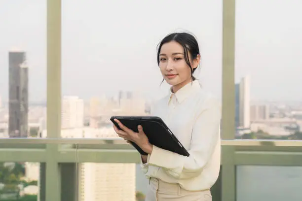 A young Asian woman on a balcony with a tablet, AI-generated.