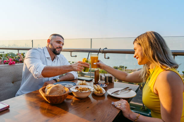 istock Young Couple Cheering With Drinks While Having Lunch In A Restaurant In Kuwait City 2007374278