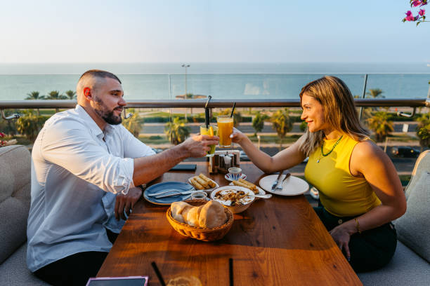 istock Young Couple Cheering With Drinks While Having Lunch In A Restaurant In Kuwait City 2007376977