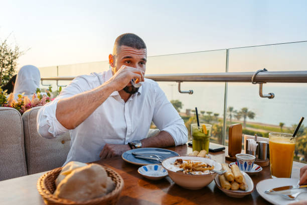 istock Young Man Drinking Coffee Before Having Lunch In A Restaurant In Kuwait City 2007378063
