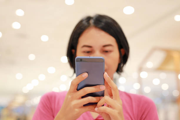 istock Close up Asian woman using smartphone on table at department store. 2007383370