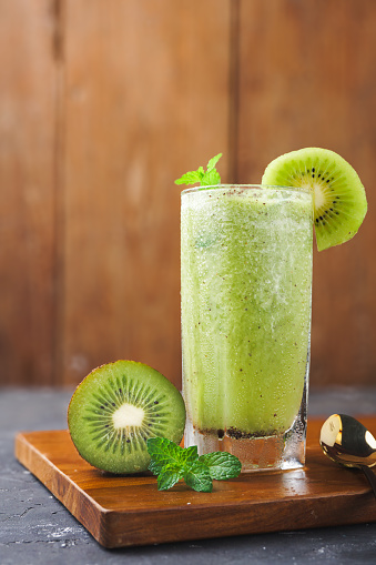 a glass of kiwi fruit juice, on a wooden background