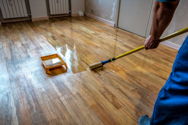 istock Parquet floor renovation. Lacquering wood floors. Worker uses a roller to coating floors 2007408405