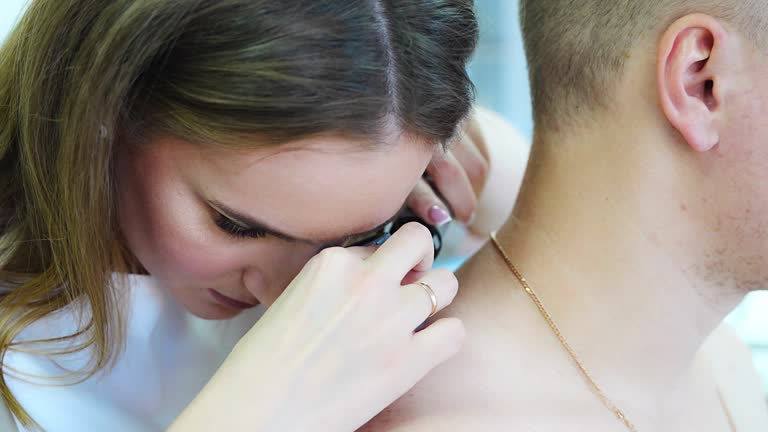 Doctor dermatologist examines skin of patient. Dermatoscopy, prevention of melanoma, skin cancer.