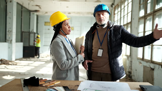 Two architects looking at the architectural project at the construction site