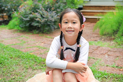 Beautiful little Asian child girl in the nature garden.