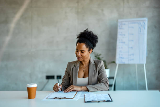 istock Female professional is sitting on chair. She is making notes in office. 2007427535