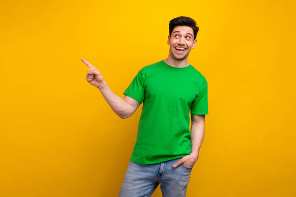 istock Photo of excited smiling funny guy point finger empty space recommend new web design studio ad isolated on yellow color background 2007451110