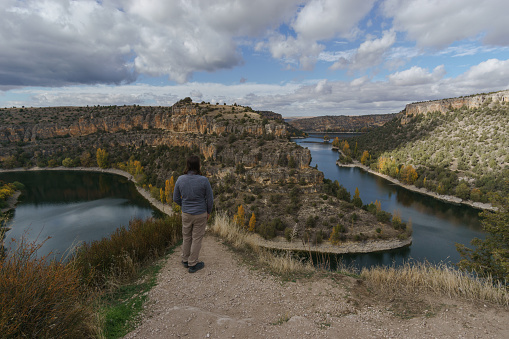 Man looking at river bend of Rio Duraton during autumn time in Hoces del Duraton natural park near Sepulveda, Segovia, Spain