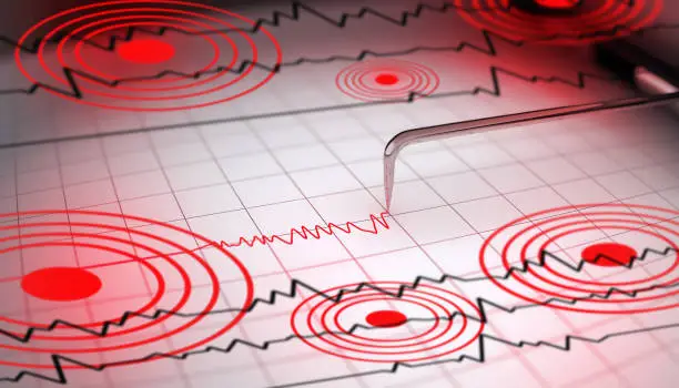Close-up of a seismograph machine needle tracing seismic waves, indicative of earthquake activity, on graph paper with epicenter rings.