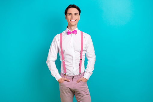 Photo portrait of handsome young guy hands pockets posing model dressed stylish pink garment isolated on aquamarine color background.