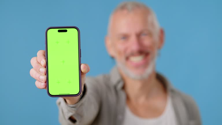 Smiling man shows mobile phone screen with green Chromakey