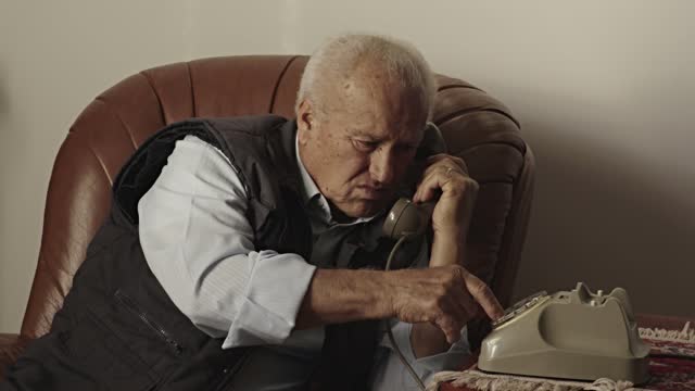 elderly alone at home dialing a phone number with an old landline phone