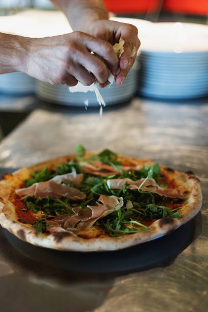 istock Chef in italian restaurant prepares pizza with prosciutto 2007521024