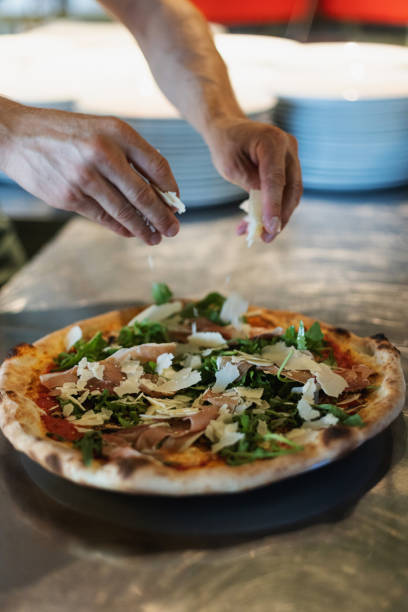 istock Chef in italian restaurant prepares pizza with prosciutto 2007523690