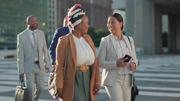 Business people, happy and walk in city with diversity, funny conversation or travel to workplace. Women, men and laugh for comic story, gossip or news with smile for chat on metro street for commute